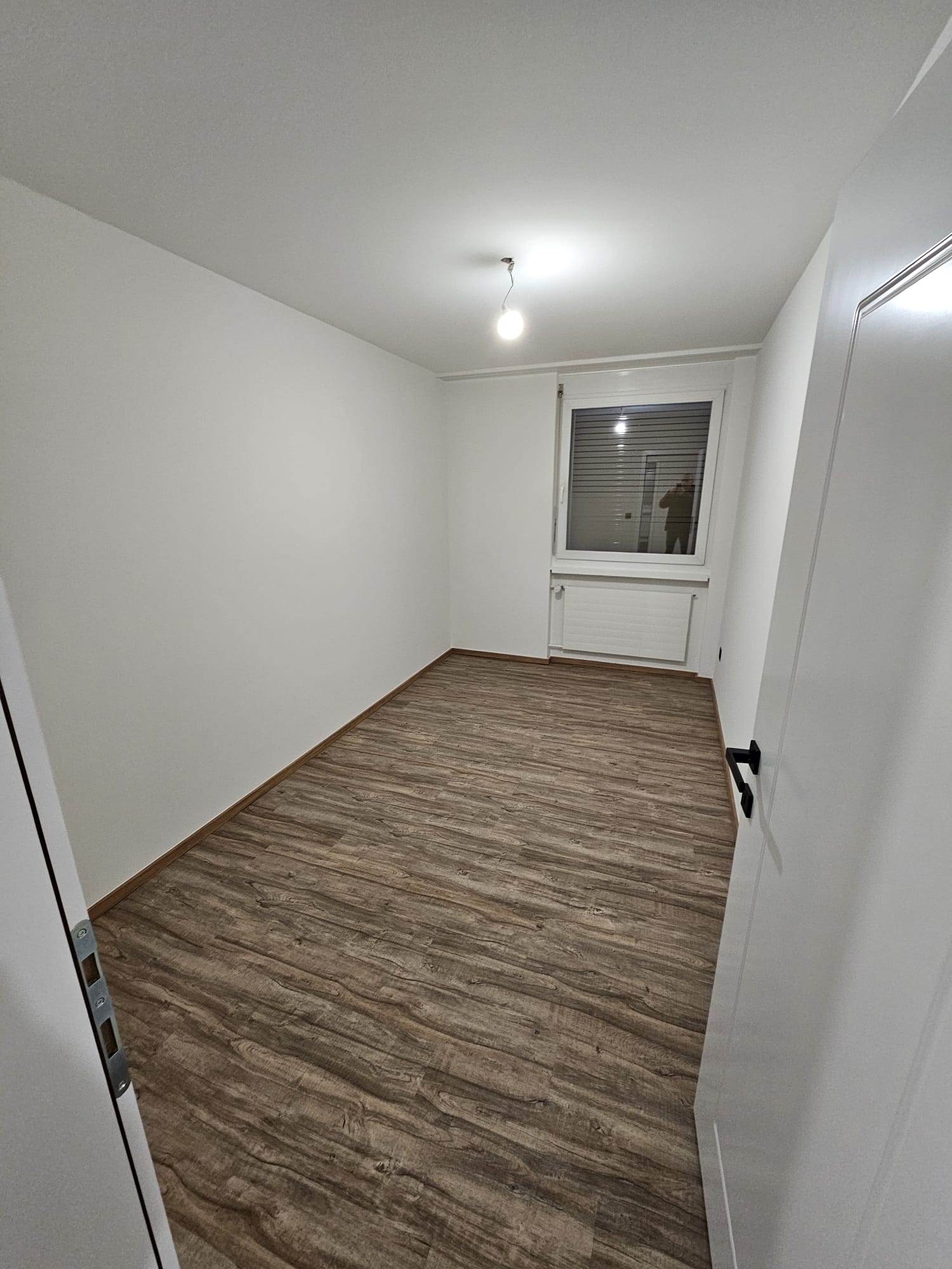 Après : murs et plafond lissés puis repeints en blanc, porte blanche, plinthes bois et sol en lames aspect bois