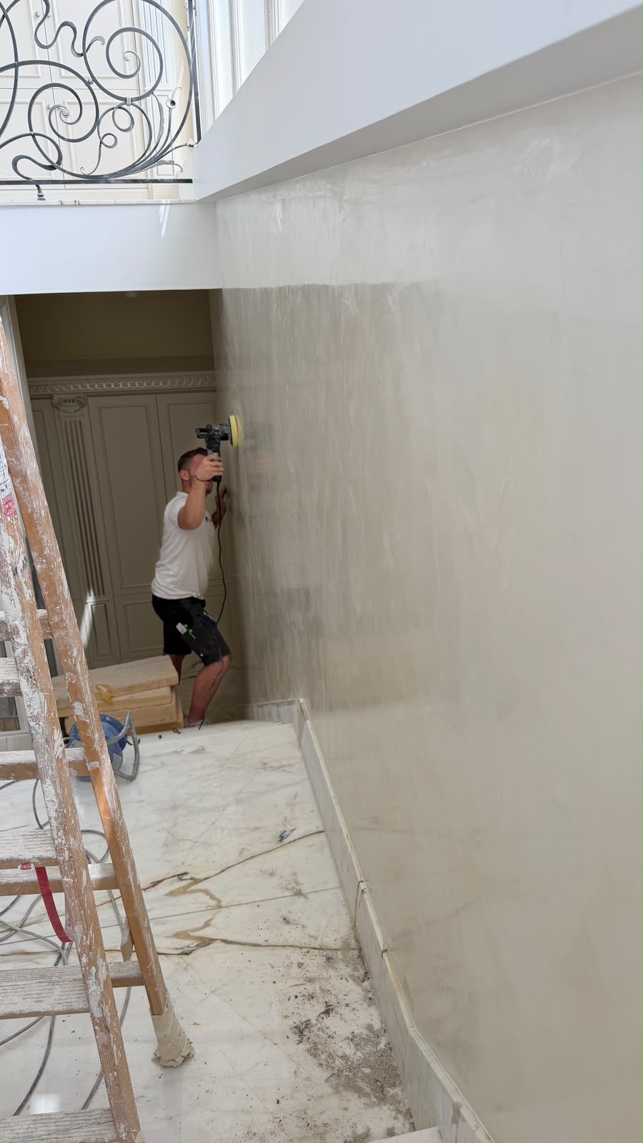 Ponçage d'un mur à la ponceuse orbitale, échelle au premier plan