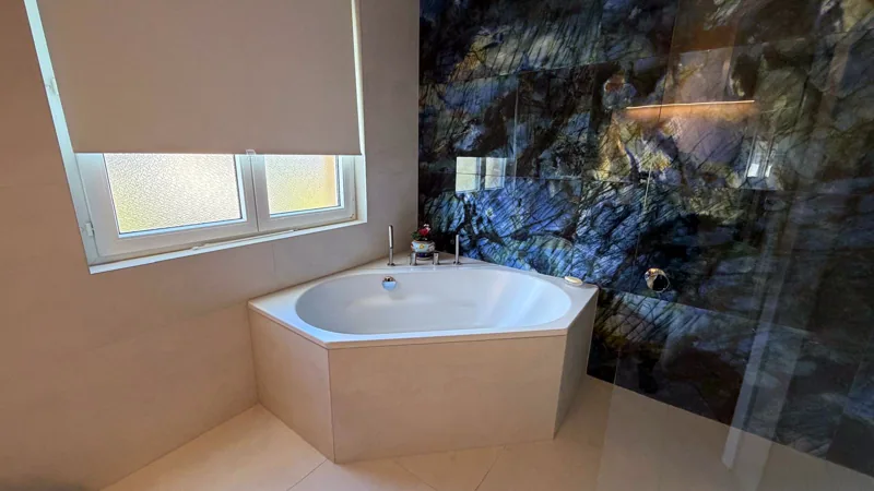 Salle de bain principale : baignoire d'angle et mur effet pierre