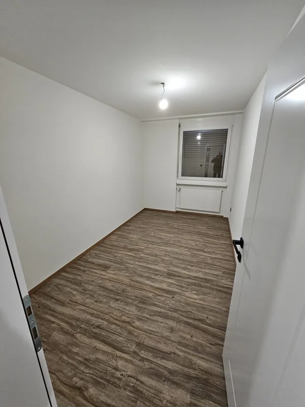 Après : murs et plafond repeints en blanc, nouveau sol imitation bois, porte et embrasure blanches