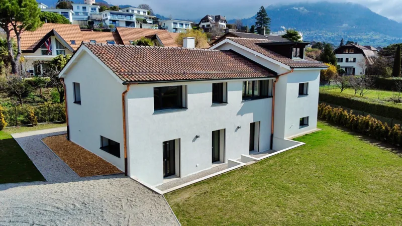 Maison à façade blanche et toit de tuiles, vue de haut, montagnes en arrière-plan
